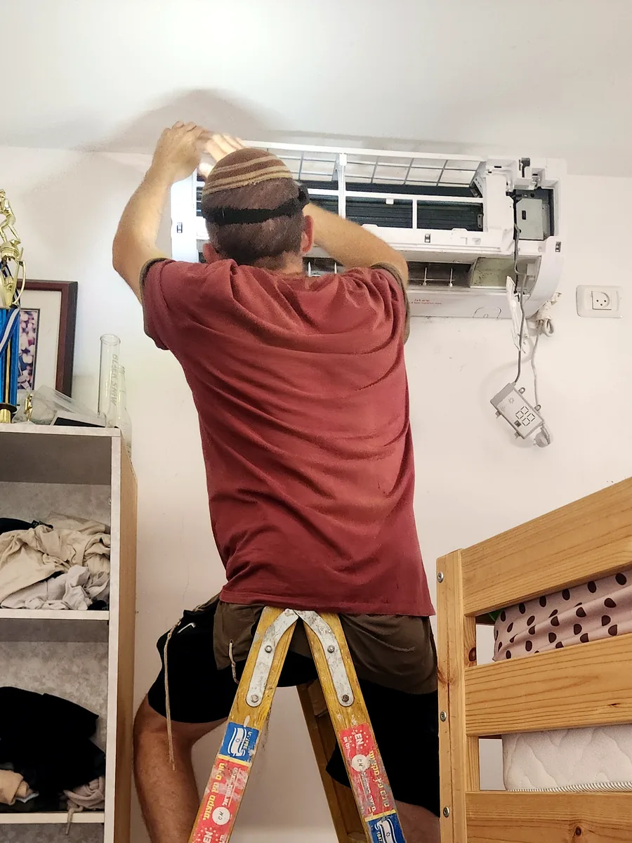 אליהו עובד על מזגן עילי בבית לקוח